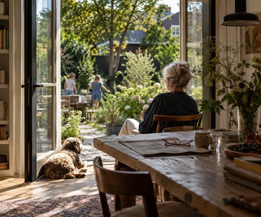 een typisch ouderen plaatje met een dame die naar haar kleinkinderen kijkt die in de tuin spelen